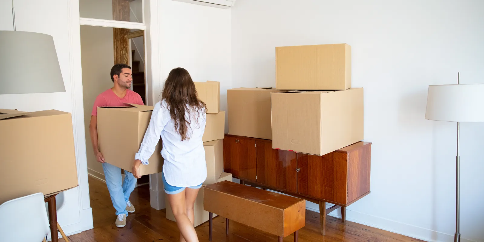 A couple carrying packed boxes while moving out of their home