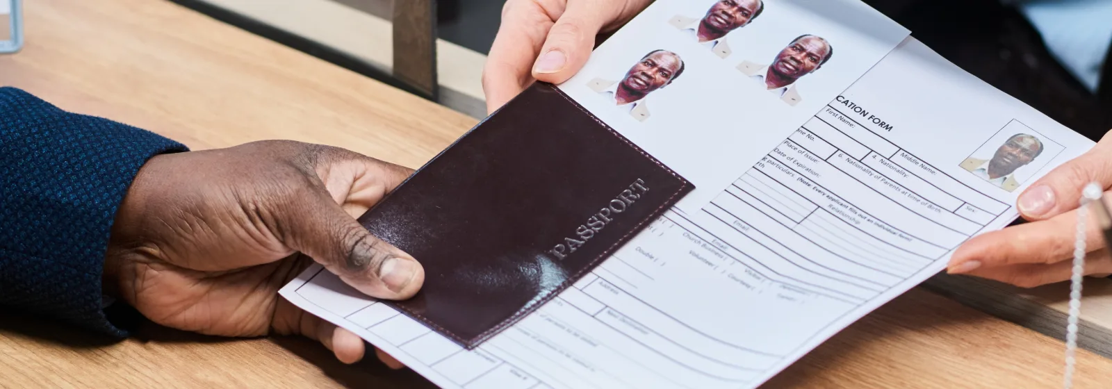 A passport and a completed application form being handed across a service counter