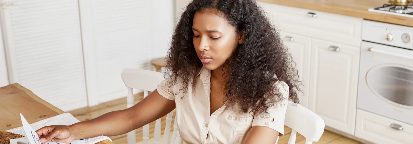 A woman working through application paperwork on a laptop at her kitchen table