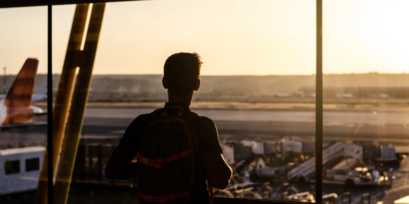 A traveller looking out over the runway from an airport terminal window