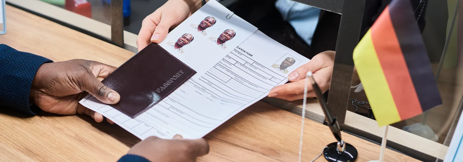 An application form and passport being handed across a desk